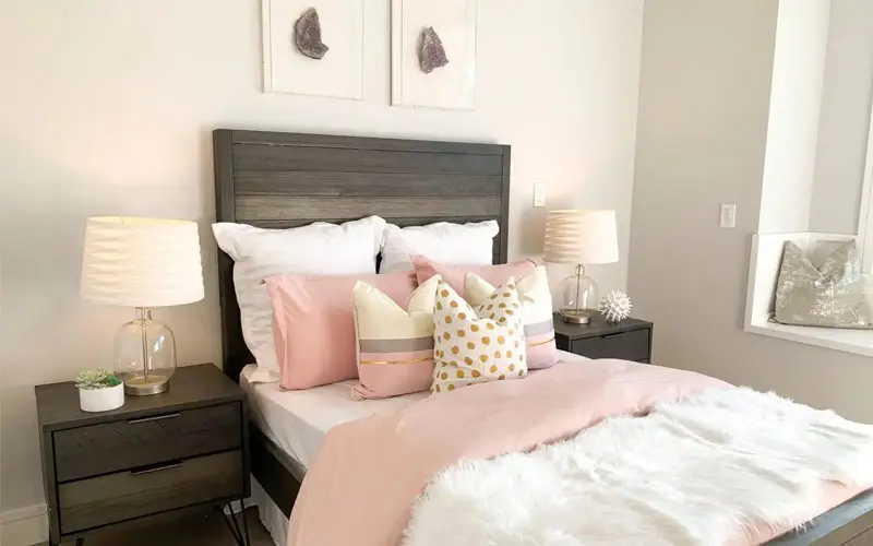 A bedroom with a bed, nightstand and two lamps.